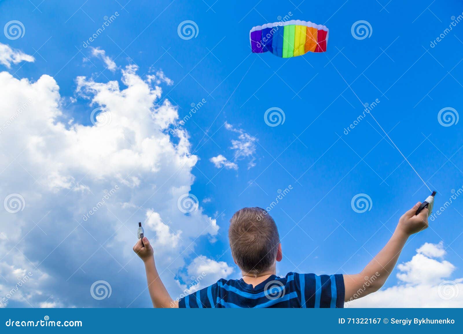 有五颜六色的风筝的男孩反对蓝天. 使用与五颜六色的风筝的男孩反对蓝天