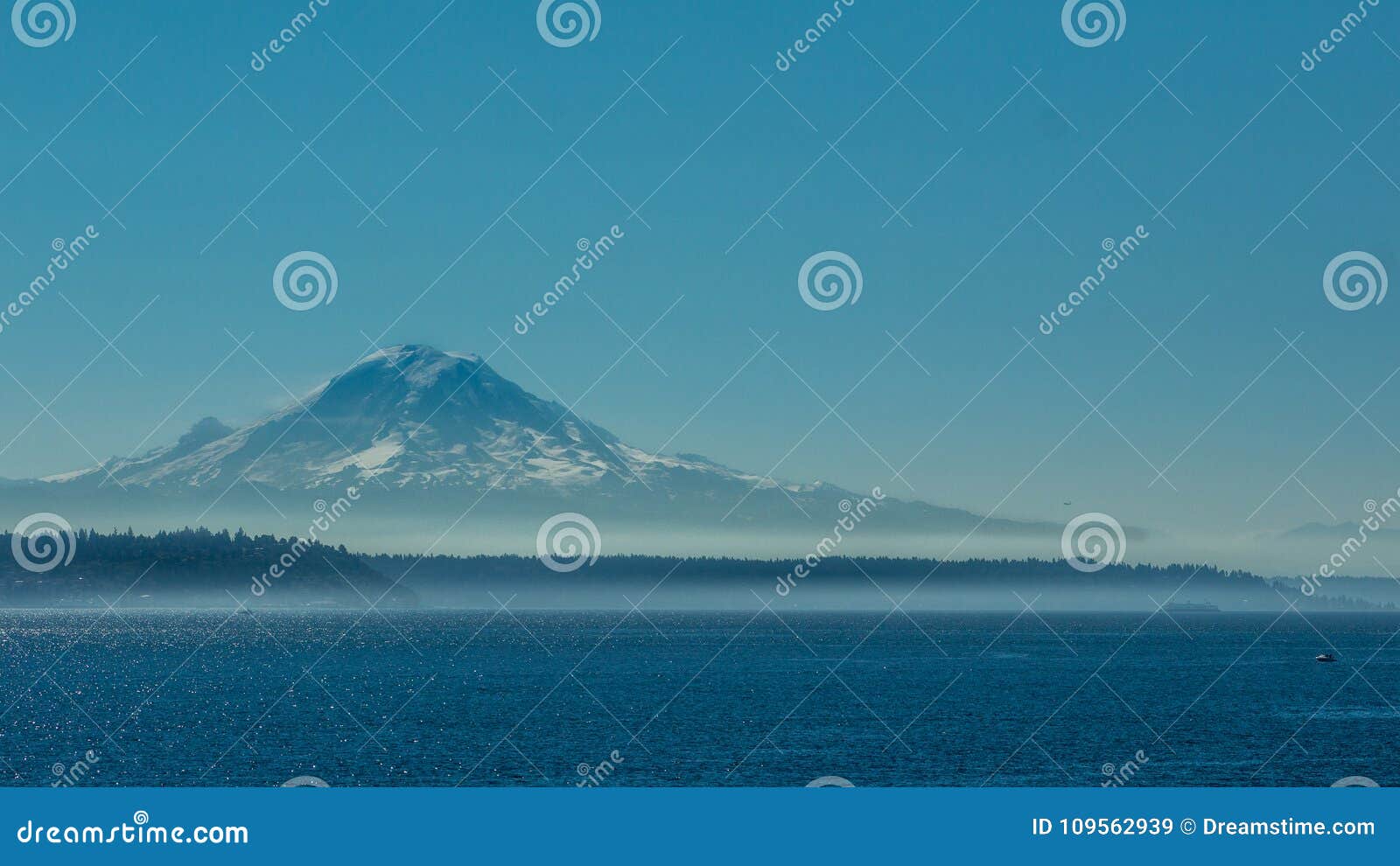 有从水观看的雪打扫灰尘的瑞尼尔山用蓝天