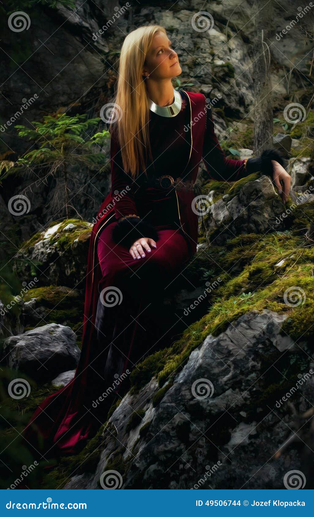 有长的金发的美丽的妇女神仙在一件历史褂子坐amids moos被盖的岩石. 有长的金发的一位美丽的妇女神仙在一件历史褂子坐在迷人forestral风景的amids moos被盖的岩石