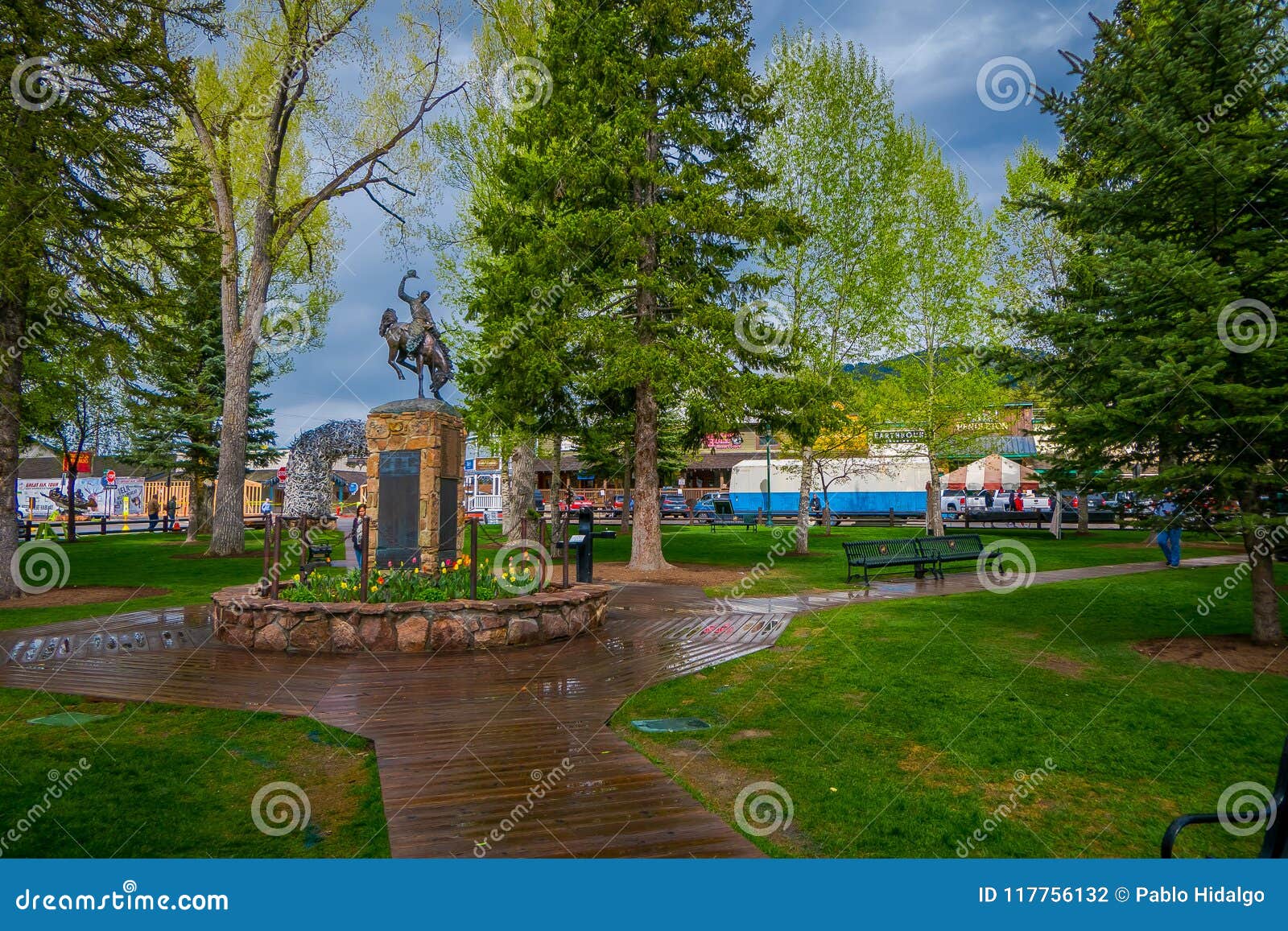 杰克逊HOLE，怀俄明，美国- 2018年5月23日：的游人走在接近牛仔一个古铜色雕象的一个公园的室外观点马的在镇中心在杰克逊怀俄明，美国