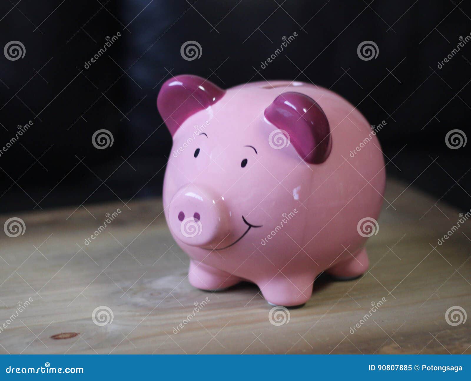 桃红色微笑贪心硬币银行存金钱. 桃红色和紫色雨天白色背景的猪动画片陶瓷财富存贮在木桌上
