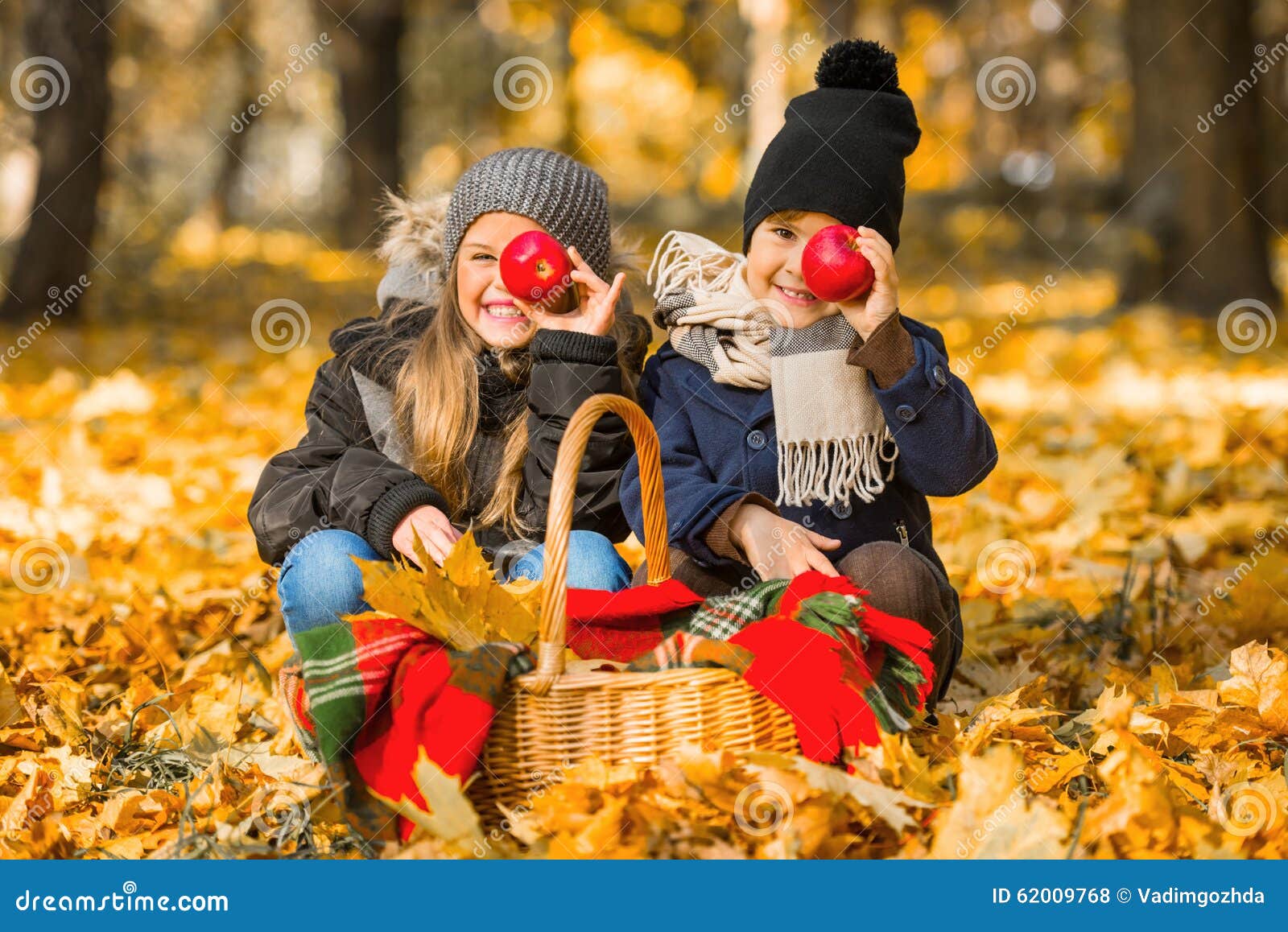 步行秋天公园. 吃红色苹果的愉快的孩子，当走在秋天公园时