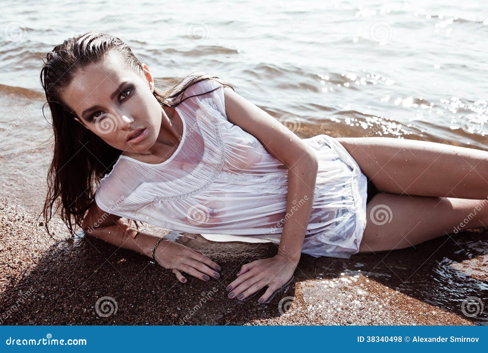 海滩的年轻性感的浅黑肤色的男人在湿T恤杉