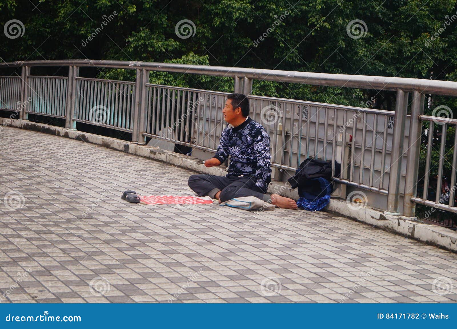 深圳，中国：一座步行天桥，一个男性叫化子. 人叫化子为在107国民路的一座步行天桥乞求 在深圳，中国