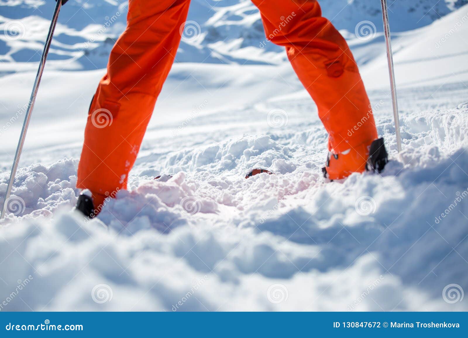 在天期间，照片在橙色裤子，在冬天轨道的滑雪杆的滑雪者腿