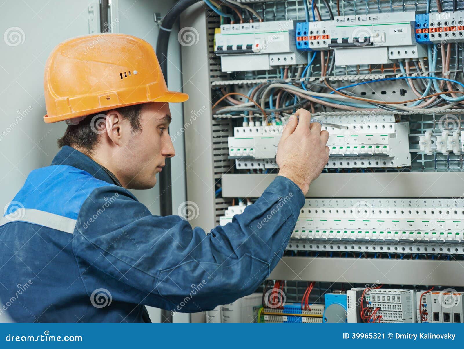 年轻成人在保险丝箱子的电工建造者工程师拧紧的设备.