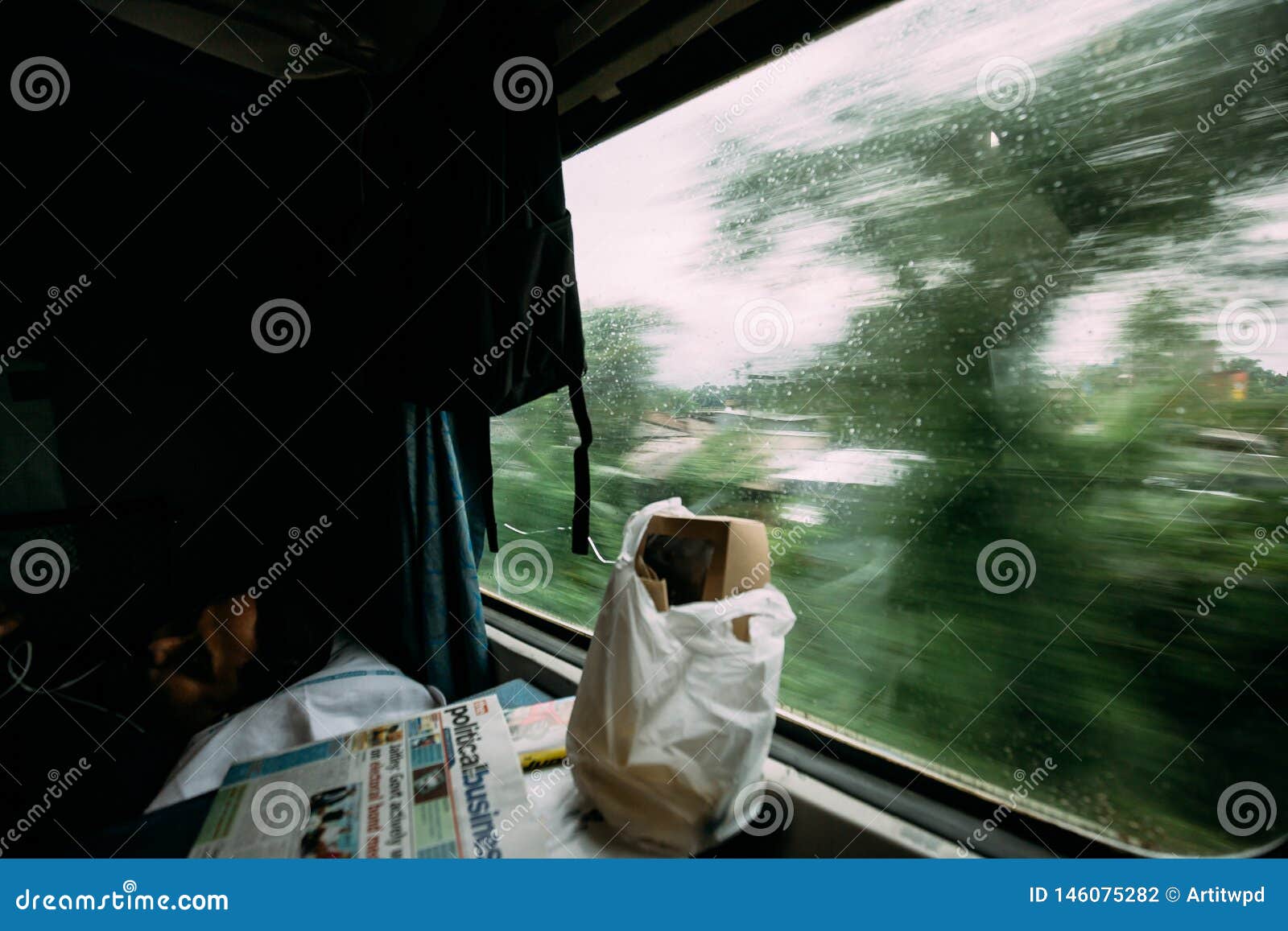 睡觉用食物和报纸的印度人，当移动与在外部时的绿色树行动迷离的火车. 睡觉用食物和报纸的印度人，当移动与在外部的绿色树行动迷离的火车从豪拉连接点火车站在加尔各答，印度时