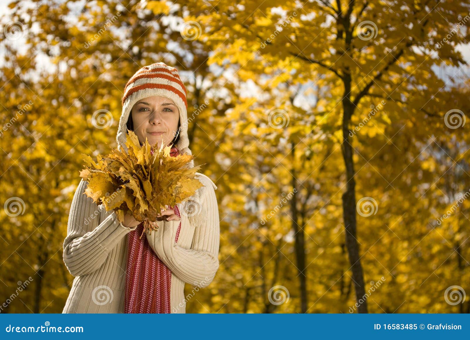 一个女人摸着耳机在拍照年轻女人摸着耳机，在公园里看着相机 图片下载 - 觅知网
