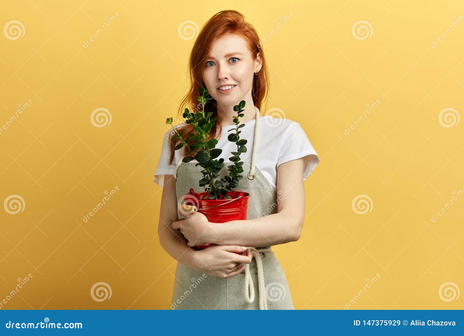 美好的快乐的女性garderner生长花. Beautiful cheerful female garderner has grown a flower, isolated yellow background, studio shot.hobby. sale