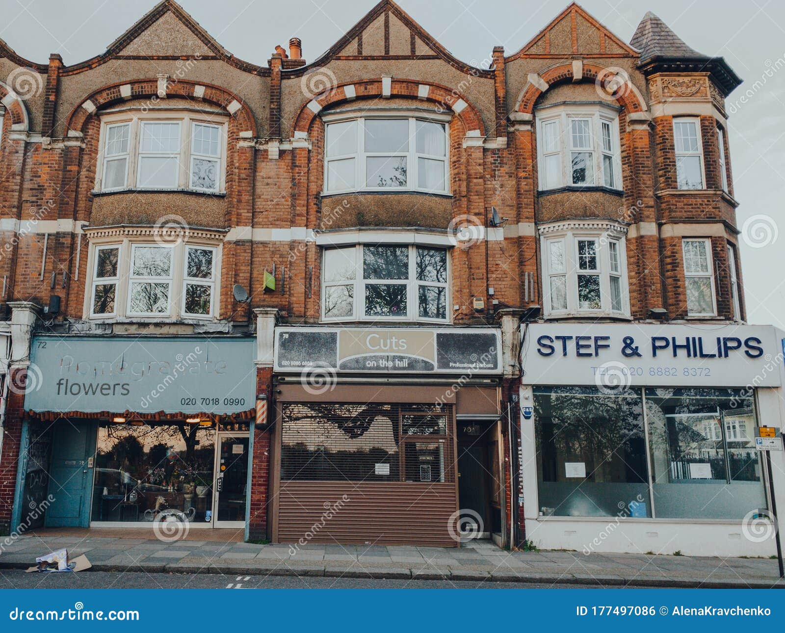 英国伦敦帕默斯格林街道上关闭的花店、理发店和房地产代理商. 英国伦敦 — 2020年3月28日：伦敦帕尔默斯格林的一条街上，关闭的花店、理发店和房地产代理商业务，因为冠状病毒威胁导致非必要业务关闭