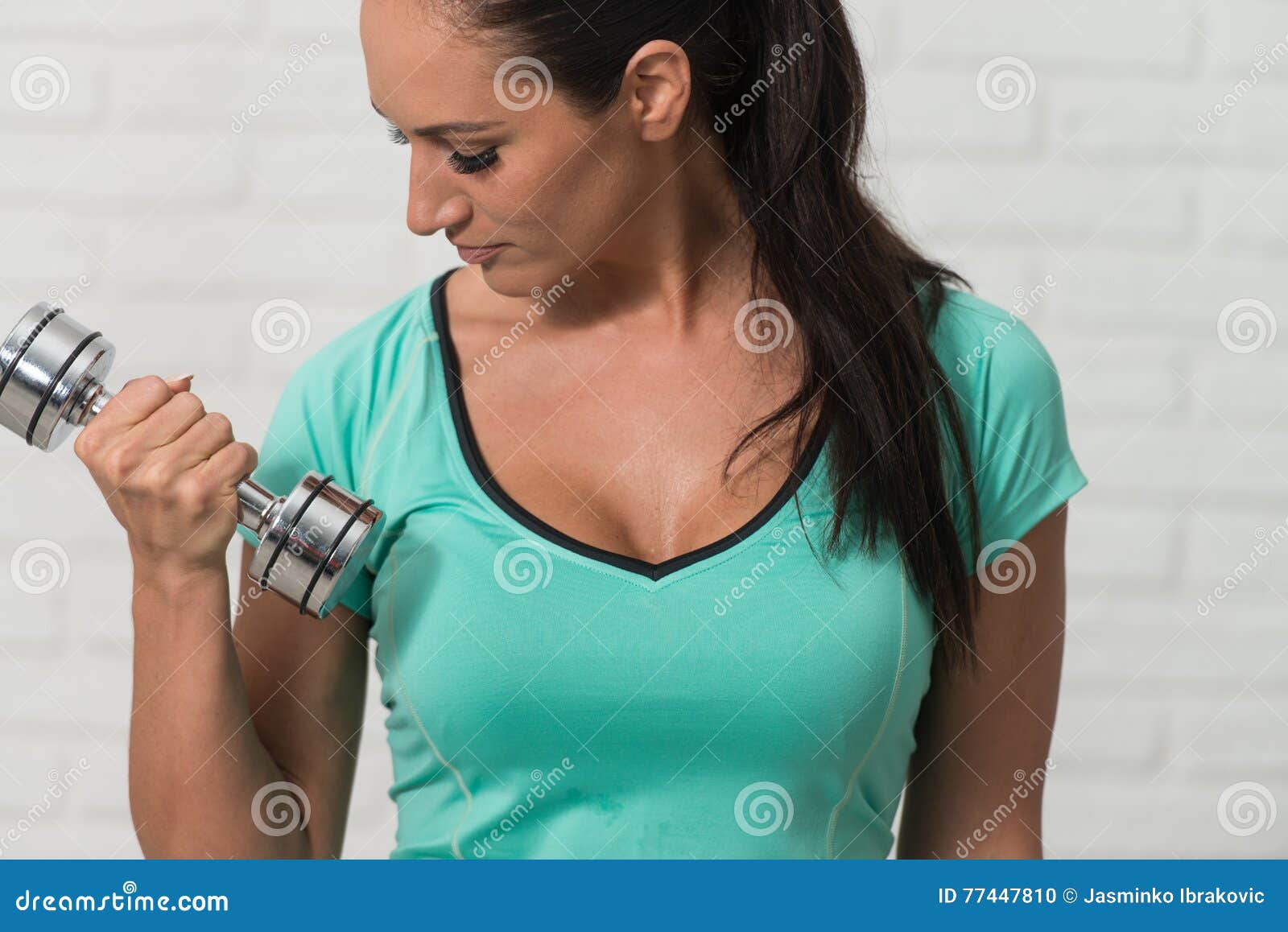 女性健美运动员用哑铃训练二头肌。图片-商业图片-正版原创图片下载购买-VEER图片库
