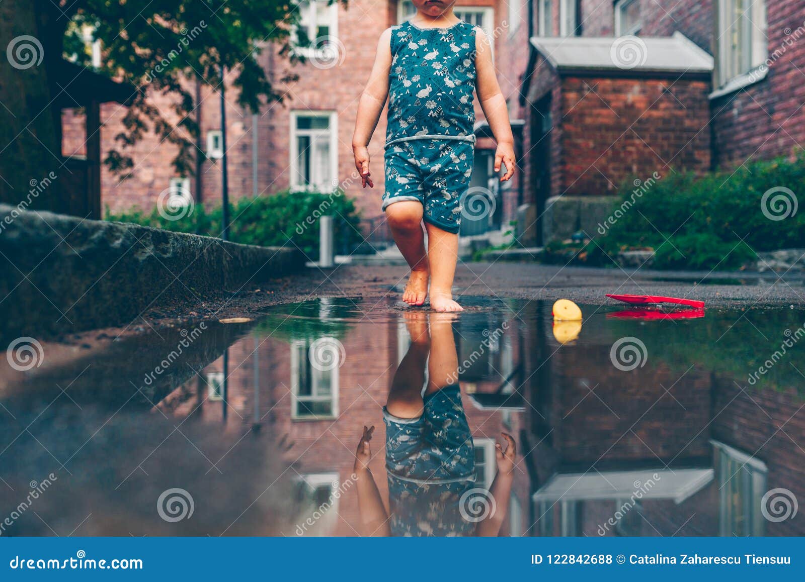 穿红色雨靴的孩子跳进水坑里。闭合。孩子在玩水玩得很开心。温暖的夏雨和快乐的孩子。。图片免费下载-5001747012-千图网Pro