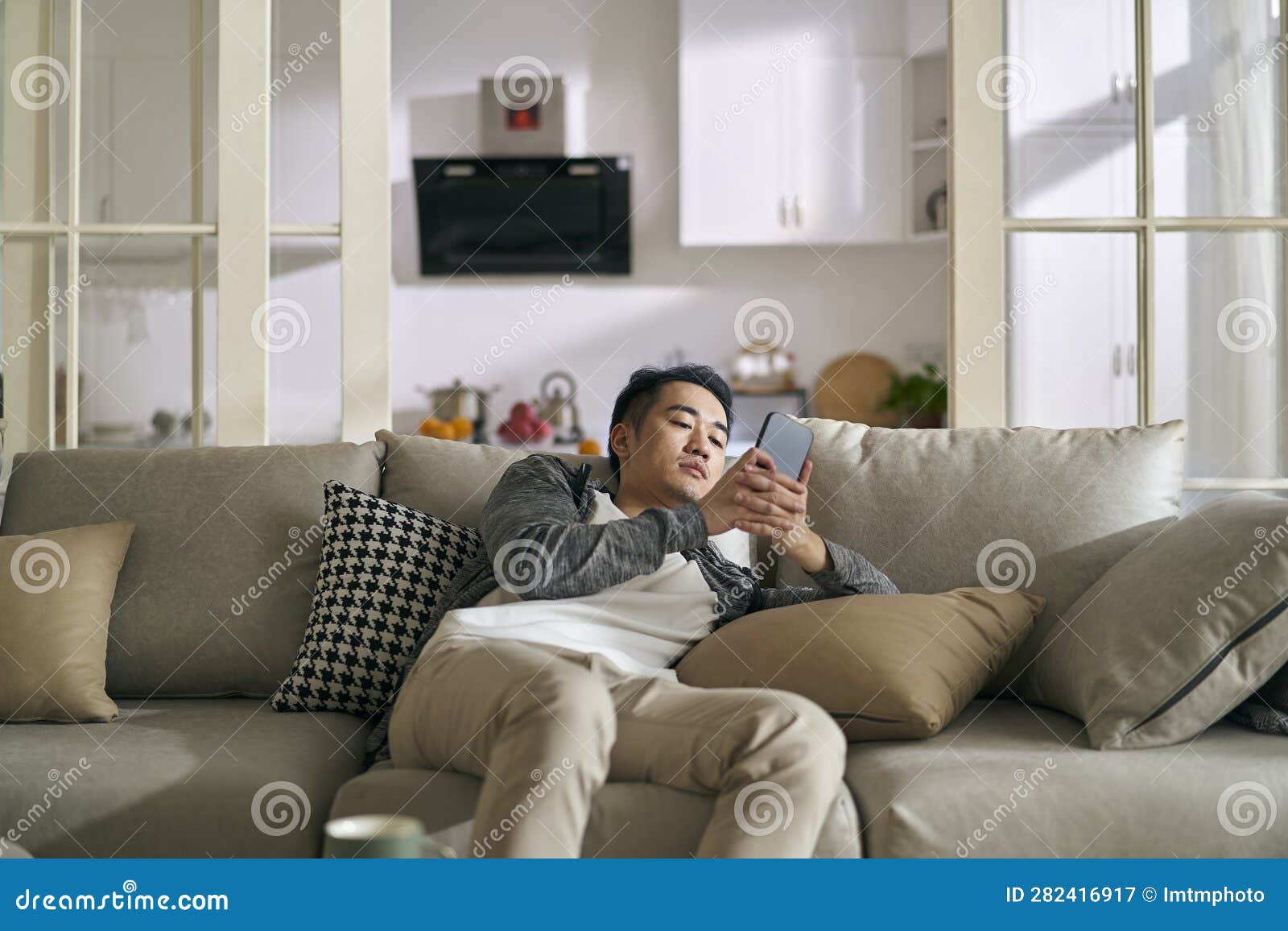 年轻人在沙发上玩智能手机照片摄影图片_ID:153735106-Veer图库