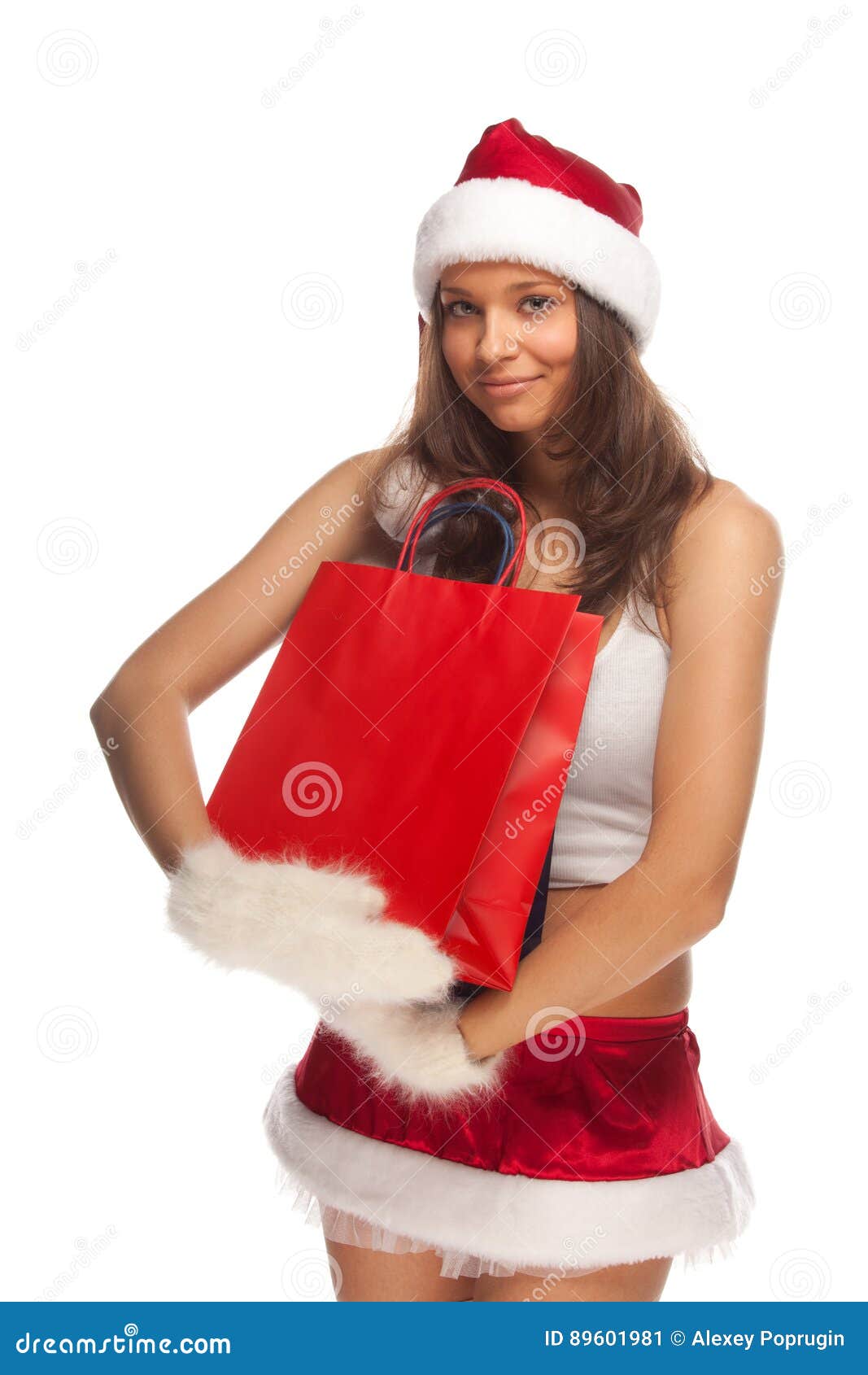 辅助工s圣诞老人. 佩带圣诞老人的美丽的性感的女孩穿衣与纸礼物袋子在手