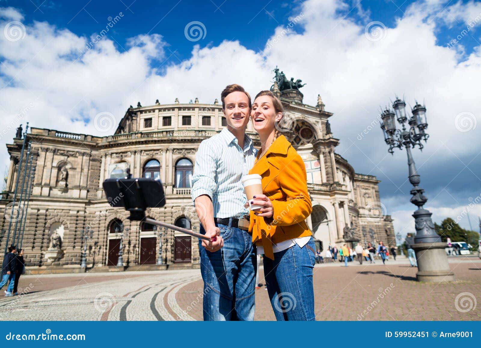 采取selfie的夫妇在Semperoper在德累斯顿. 在Semperoper的旅游夫妇在采取与电话的德累斯顿selfie在棍子