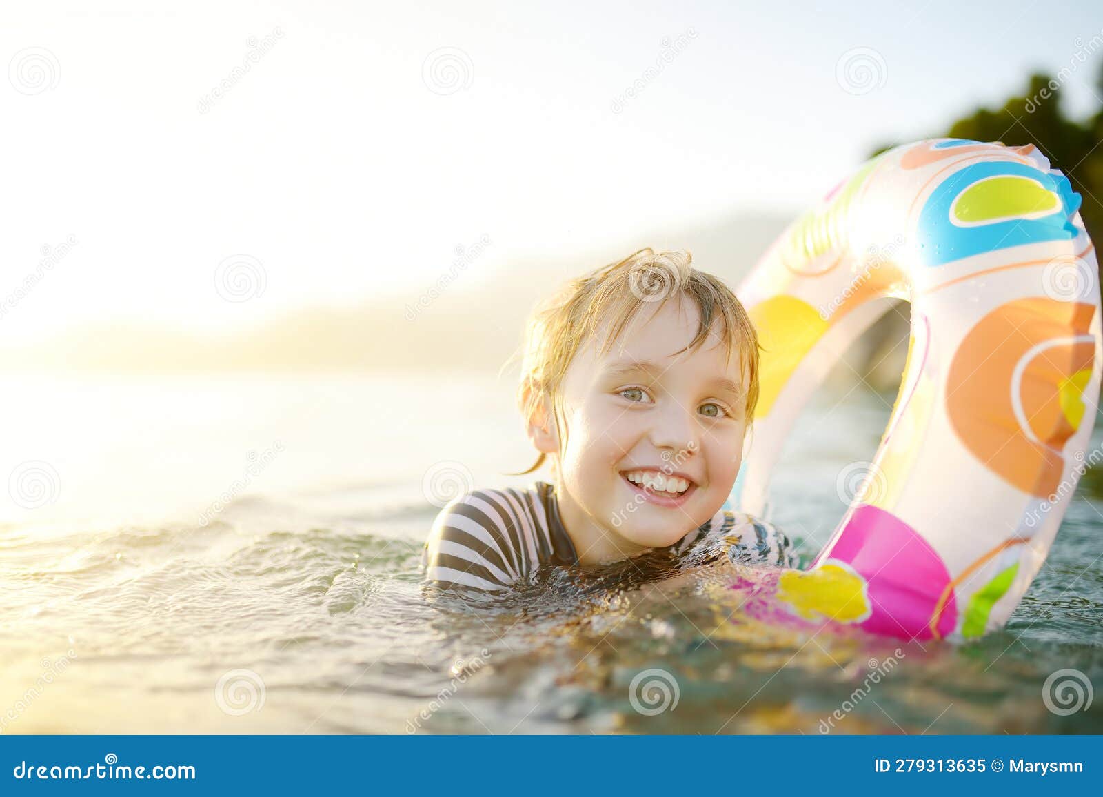 阳光明媚的夏日，小男孩拿着五颜六色的浮圈在海里游泳。可爱的孩子在沙滩上玩耍。暑期家庭和儿童度假胜地。照片摄影图片_ID:423419805 ...