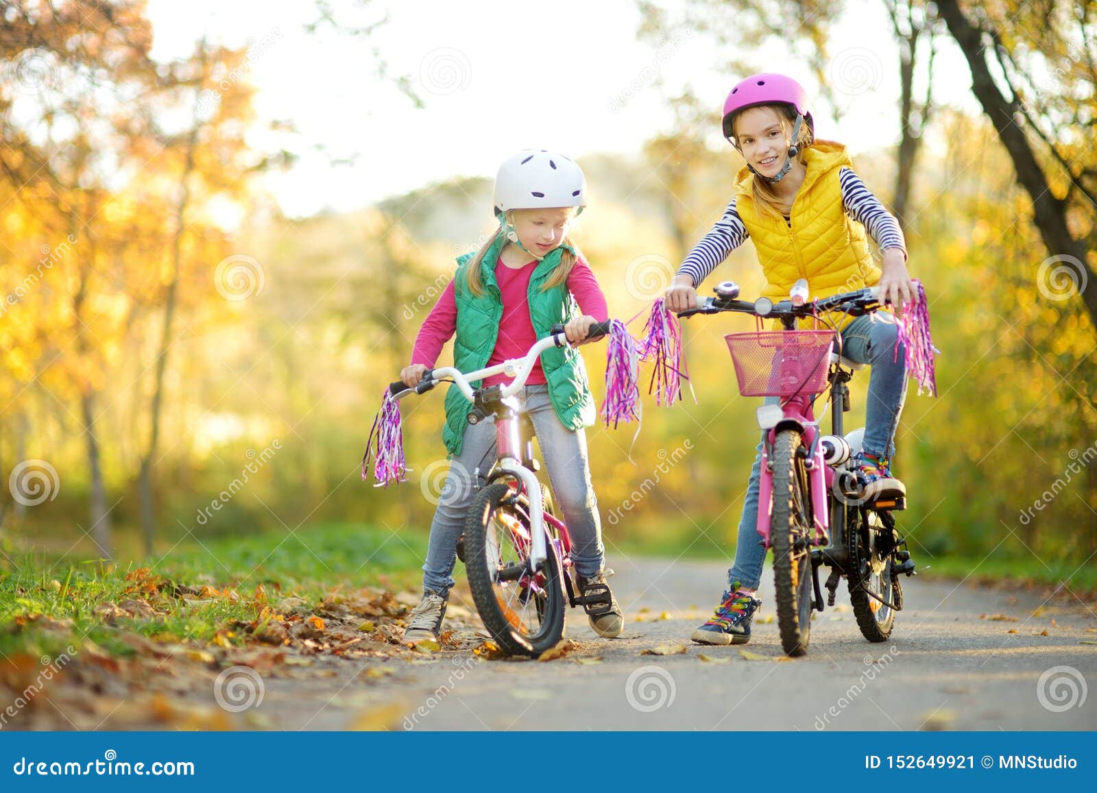 骑自行车的逗人喜爱的妹在城市公园在晴朗的秋天天 r 头戴安全帽的孩子，当骑自行车时